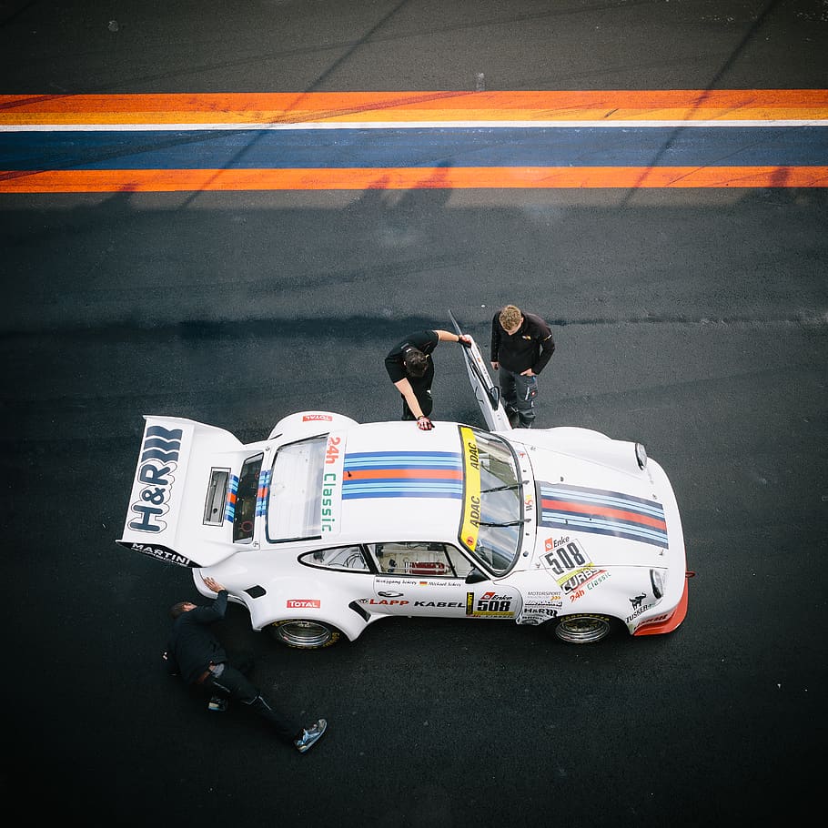 classic white Porsche 911 at pit stop with crew, transportation