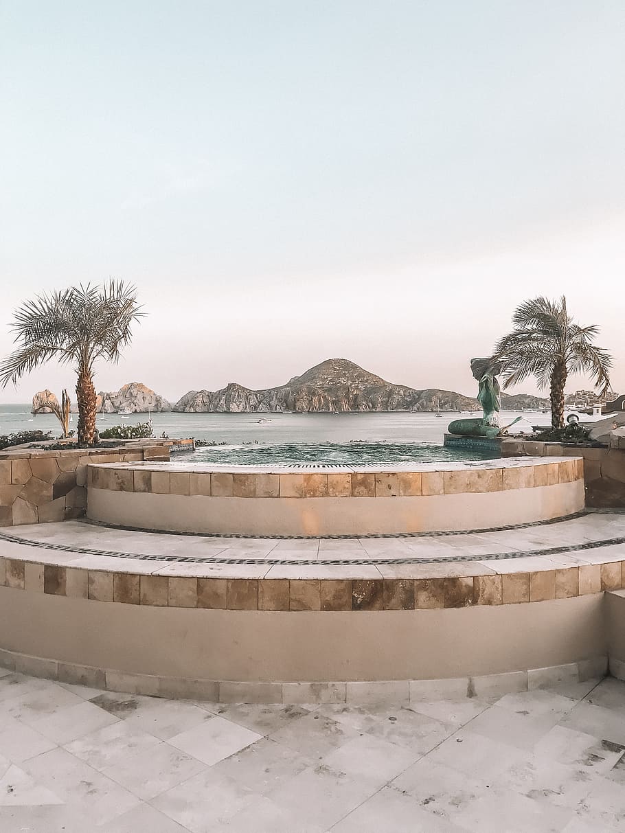 two palm trees in between pool, step, seat, water, mountain, ocean HD wallpaper