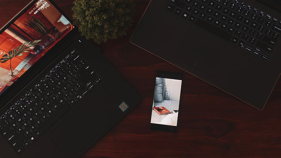 powered-on Android smartphone near two laptops, computer, table HD wallpaper