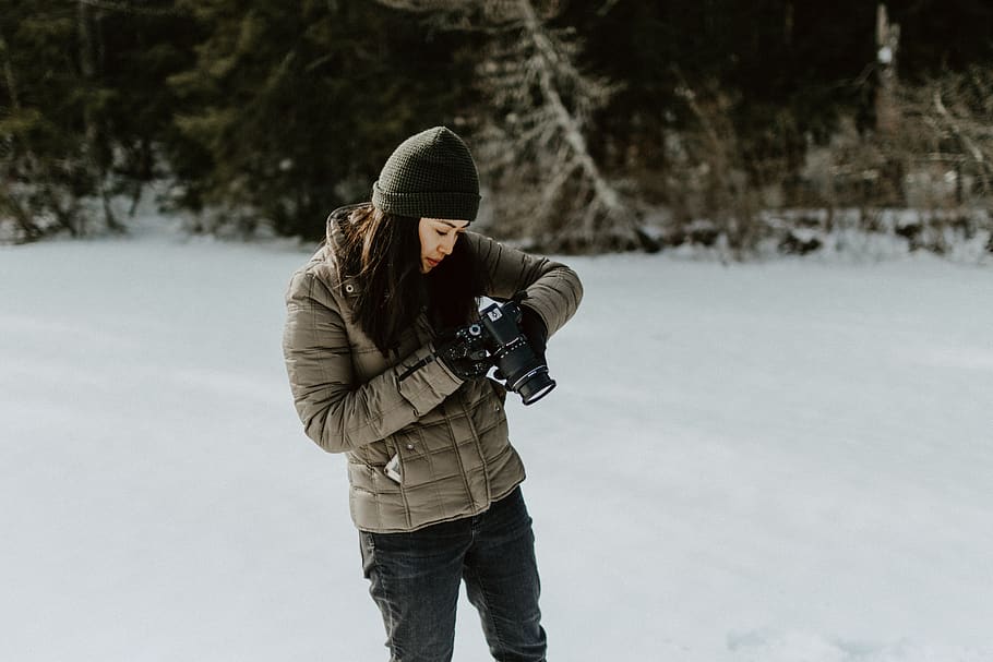 woman holding black digital camera standing on ground filled with snow, HD wallpaper