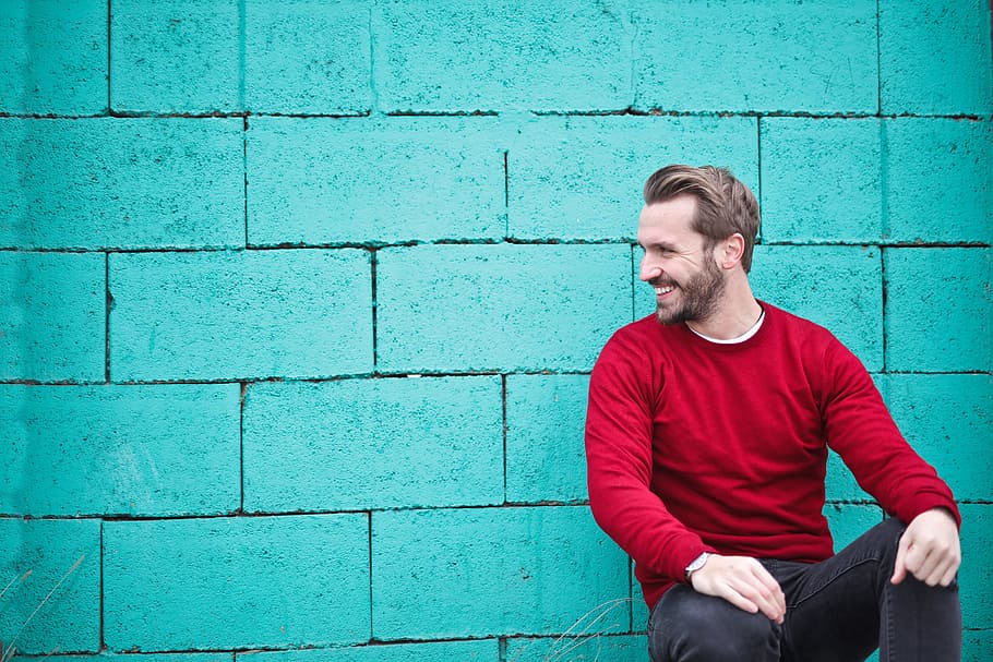 Young Adult Man wearing a red sweater leaning on a turquoise brick wall, HD wallpaper