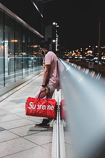 Man sitting on stairs with red Louis Vuitton X Supreme leather