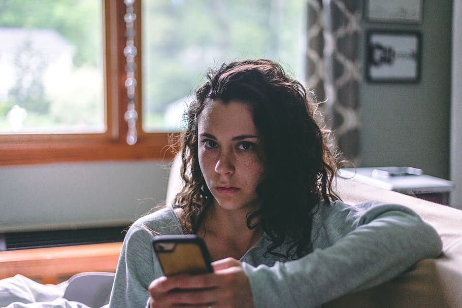 Woman Holding Phone Sitting On Sofa, brunette, couch potato, curly hair, HD wallpaper