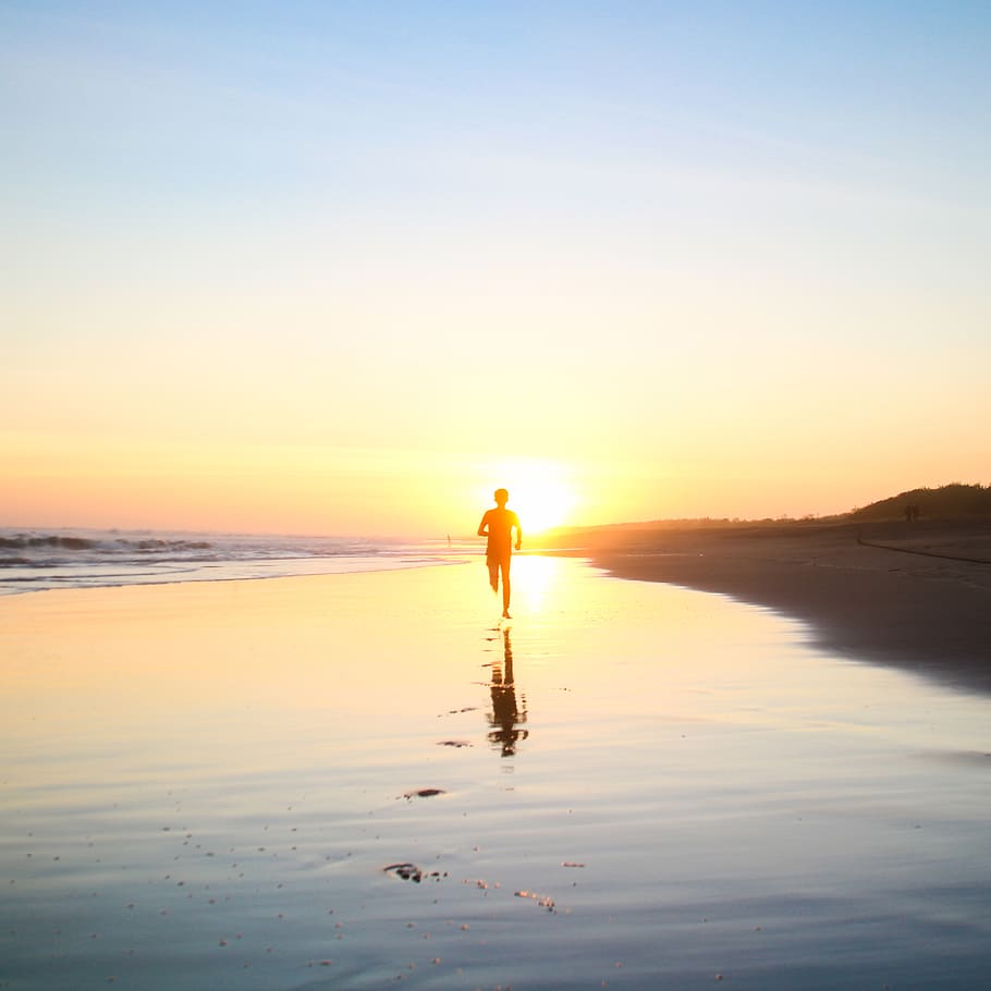 Silhouette of Boy Running in Body of Water during Sunset, backlit HD wallpaper