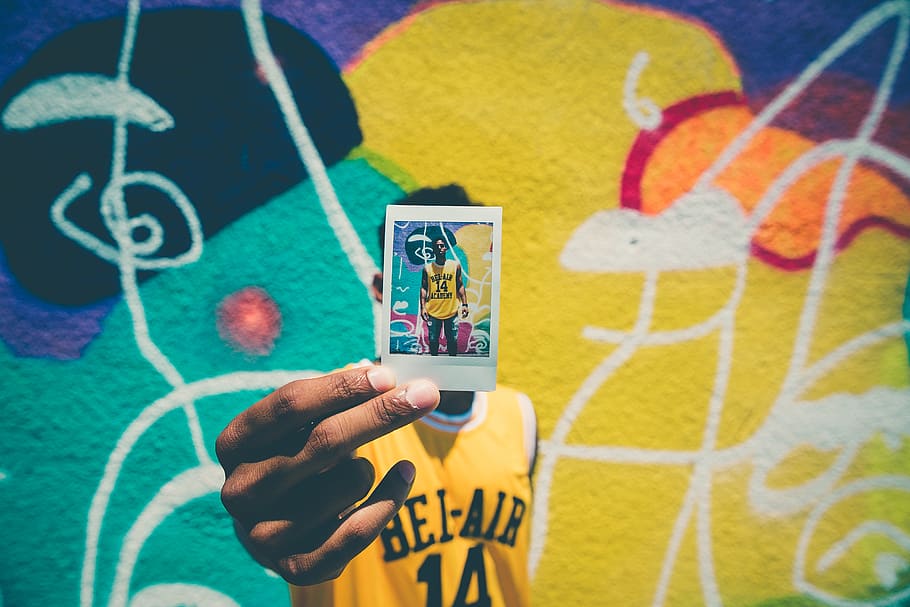 person holding printed photo of him with graffiti as background, HD wallpaper