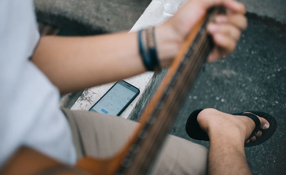 Person Holding Guitar Sitting Beside Black Smartphone, blur, casual HD wallpaper