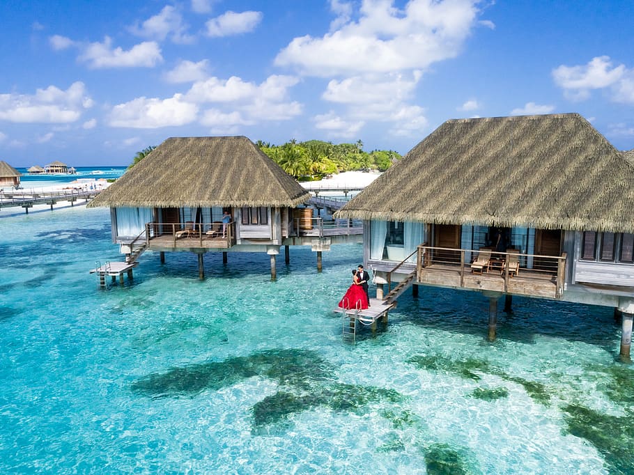 Man And Woman Standing On Deck , beach, couple, hotel, hut, lagoon HD wallpaper