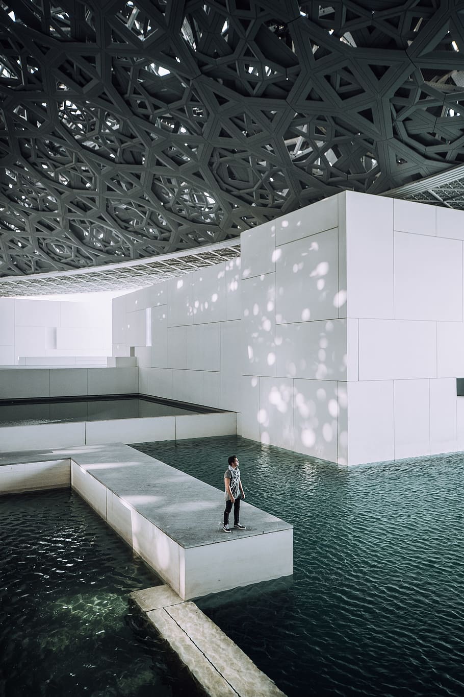 person standing near body of water inside building, pool, water feature