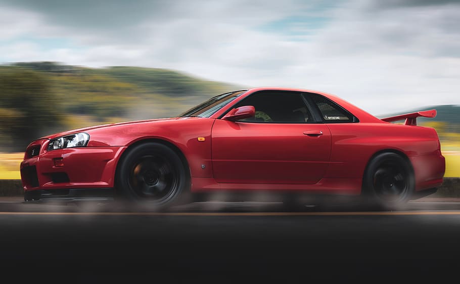Selective Focus Photography of Red Nissan Gt-r R34 Skyline Running on Road HD wallpaper