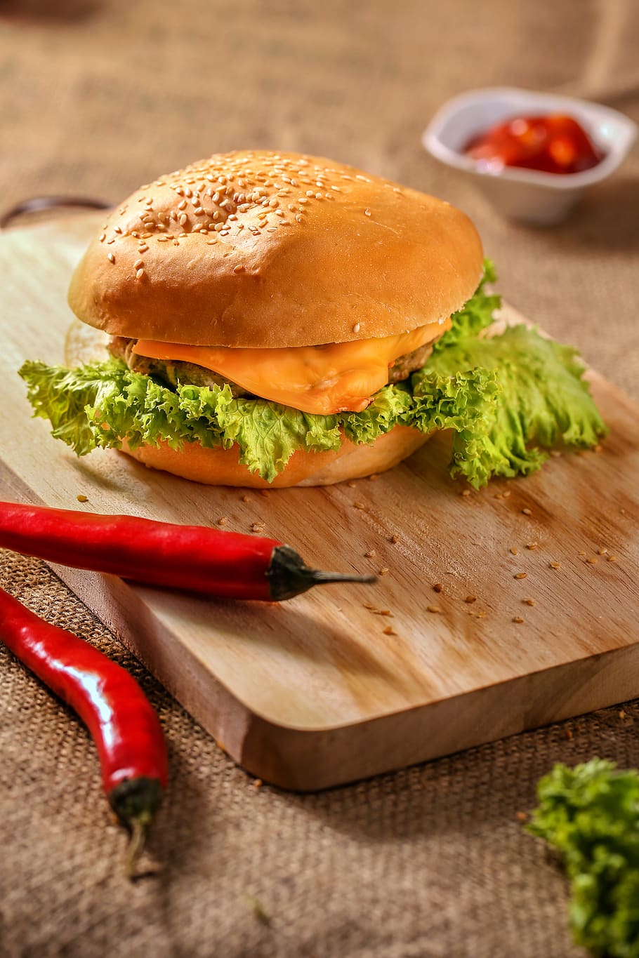Burger on Top of Wooden Board Near Two Red Chili, bread, burlap HD wallpaper