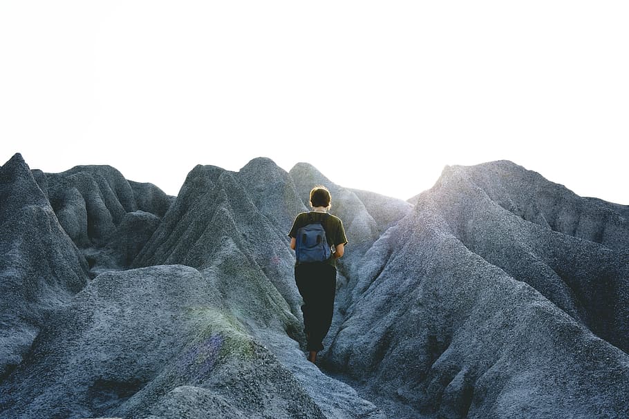 Man in Black Crew Neck Shirt and Pants Walking on Gray Mountain Formations HD wallpaper