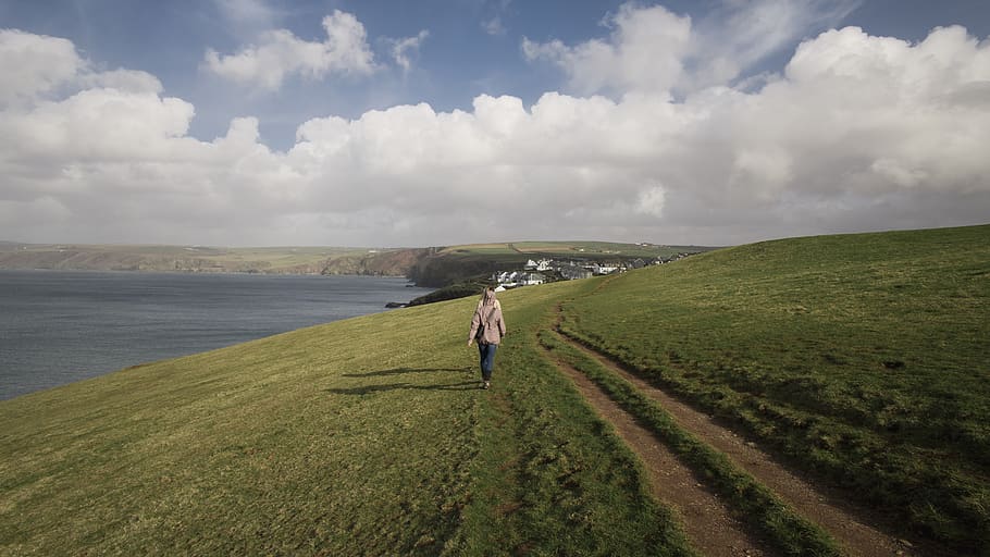Woman Walking On Green Grass Field, clouds, coast, coastal land HD wallpaper