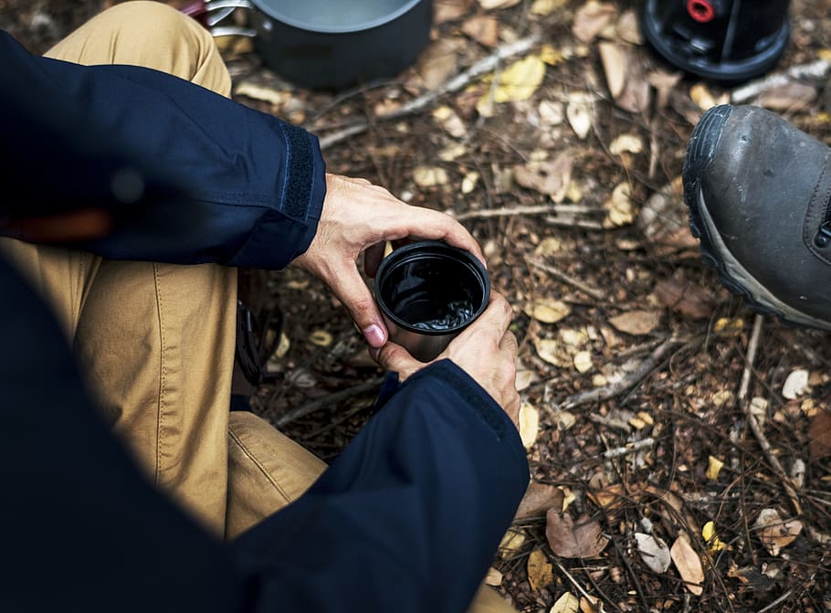Person Holding Black and Gray Travel Mug With Sitting on Ground HD wallpaper