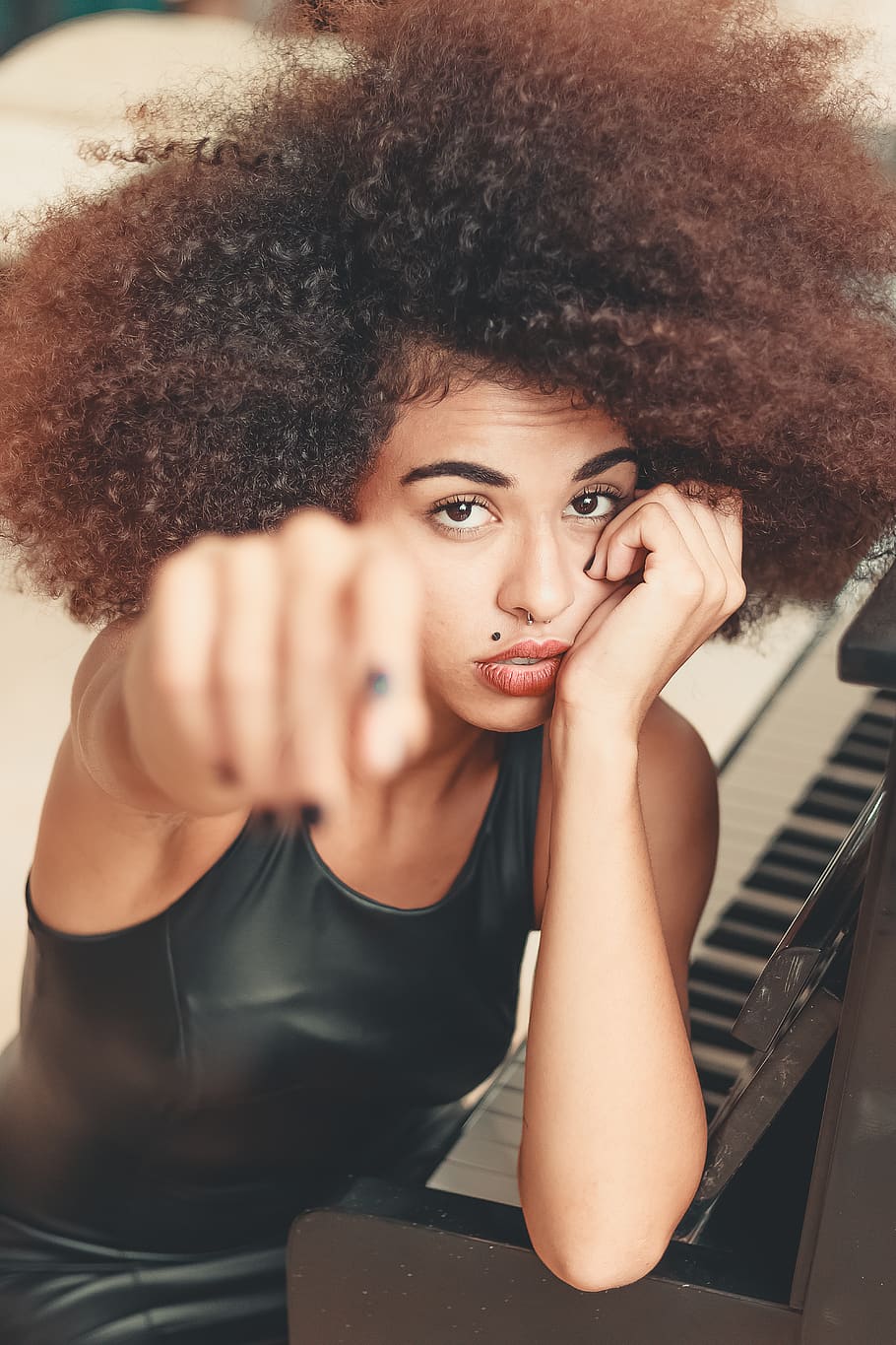 Woman Leaning on Piano While Raising Right Hand Forward, afro