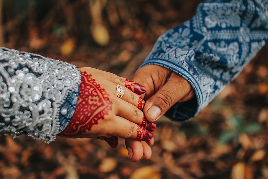 selective focus photography of man and woman holding hands, finger