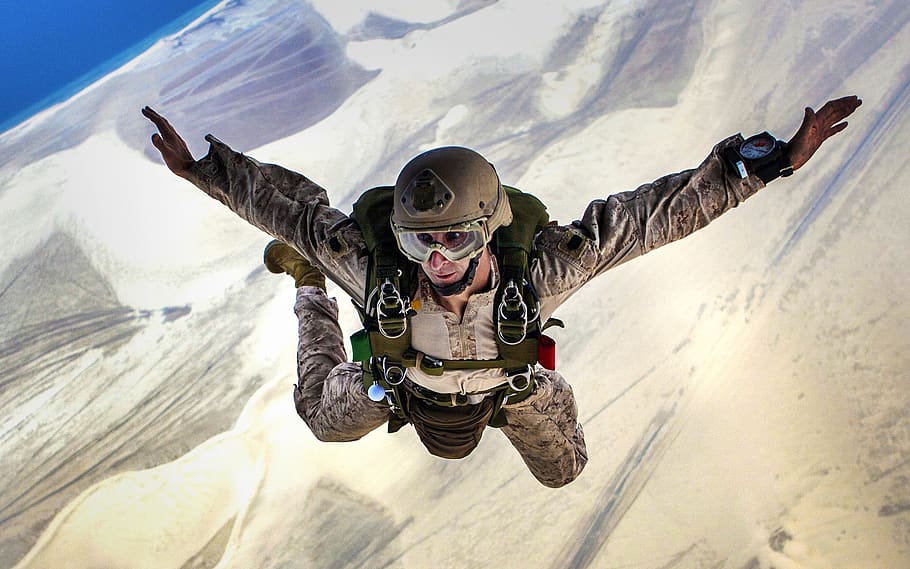 Man Wearing Brown Helmet Performing Sky Diving in Snow Covered Land Under Blue Sky during Daytime HD wallpaper