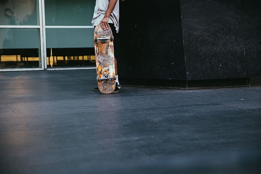 A skateboarder pauses and holds skateboard in hand, 20-25 year old HD wallpaper