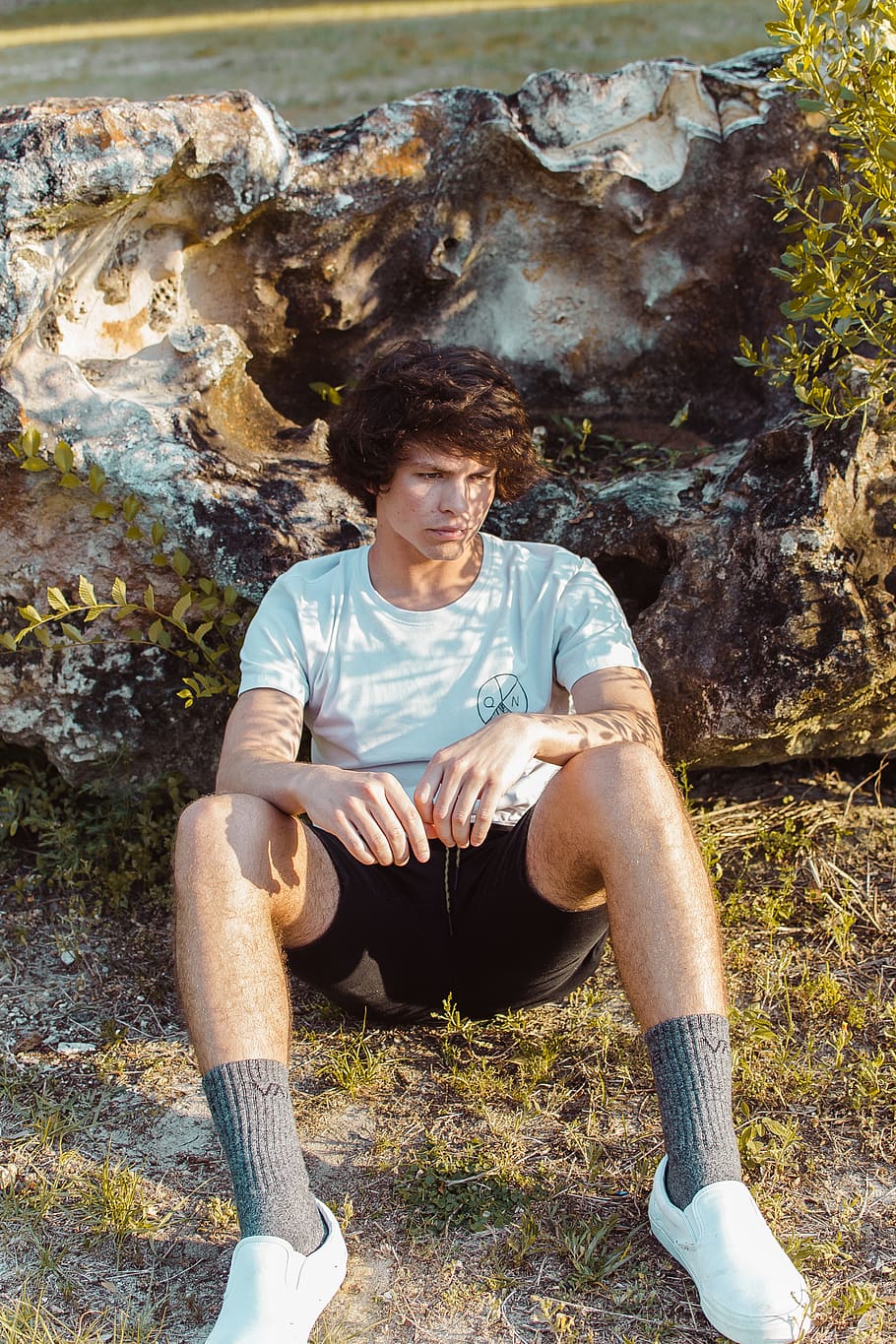 man sitting against rock, apparel, clothing, person, human, footwear HD wallpaper