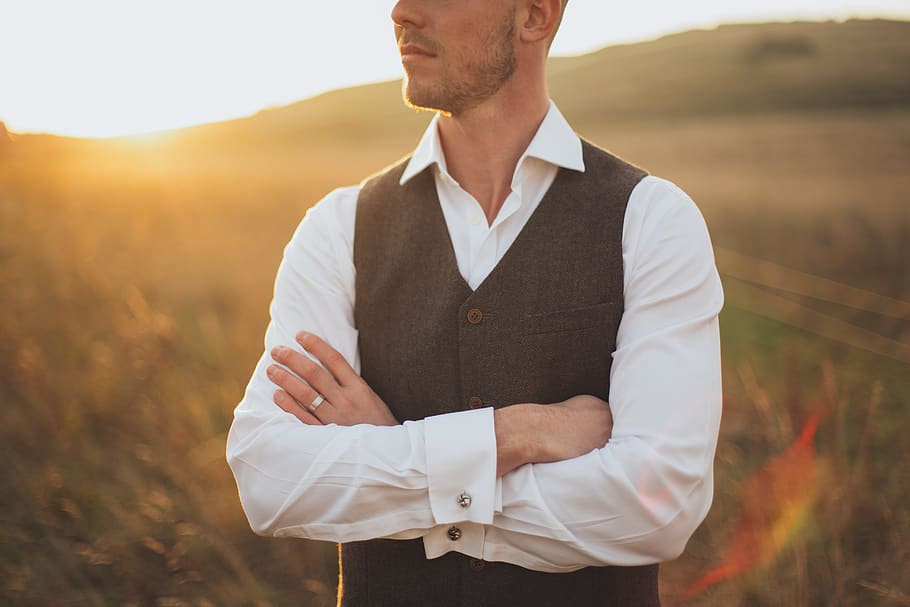 Man Wearing White Dress Shirt With Black Vest Standing on Grass Field during Sunset