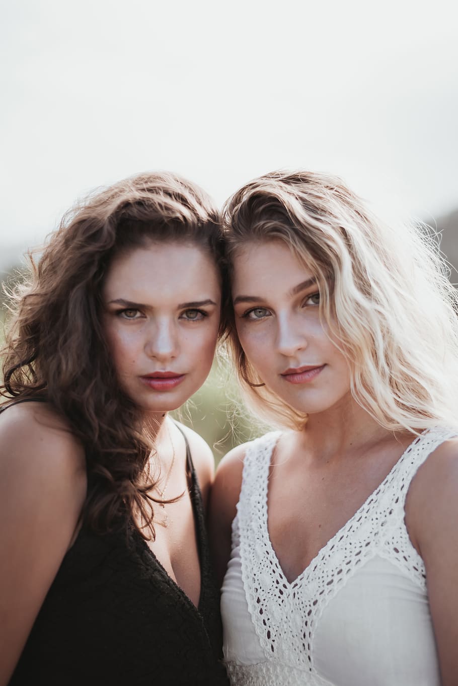 two women standing side-by-side, portrait, looking at camera HD wallpaper