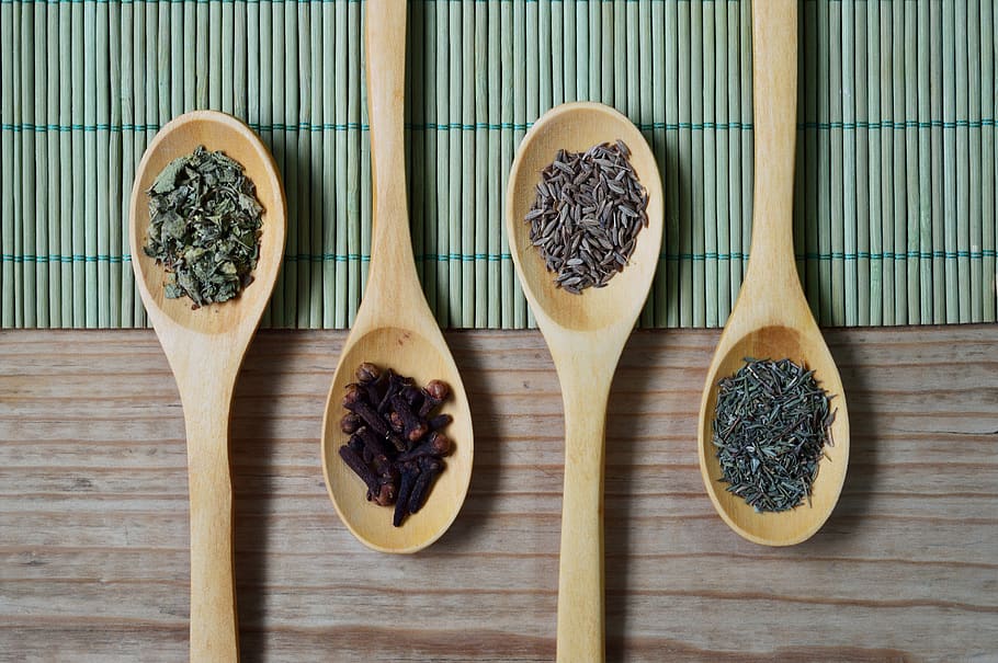 Brown Wooden Spoon With Herbs on Top of Green Bamboo Mat and Brown Wooden Surface HD wallpaper