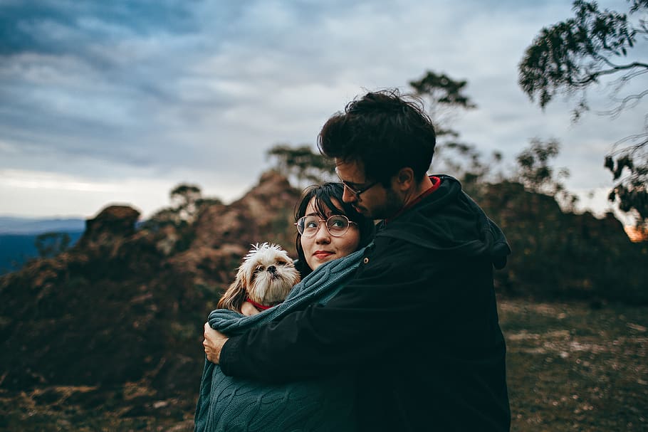 man hugging woman carrying dog, clothing, apparel, human, person