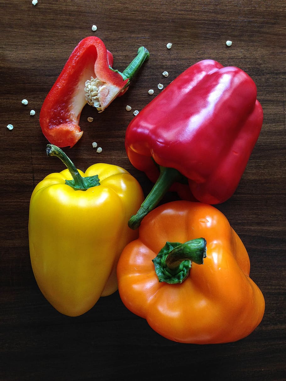 Three Yellow, Red and Orange Bell Peppers on Brown Surface, capsicum