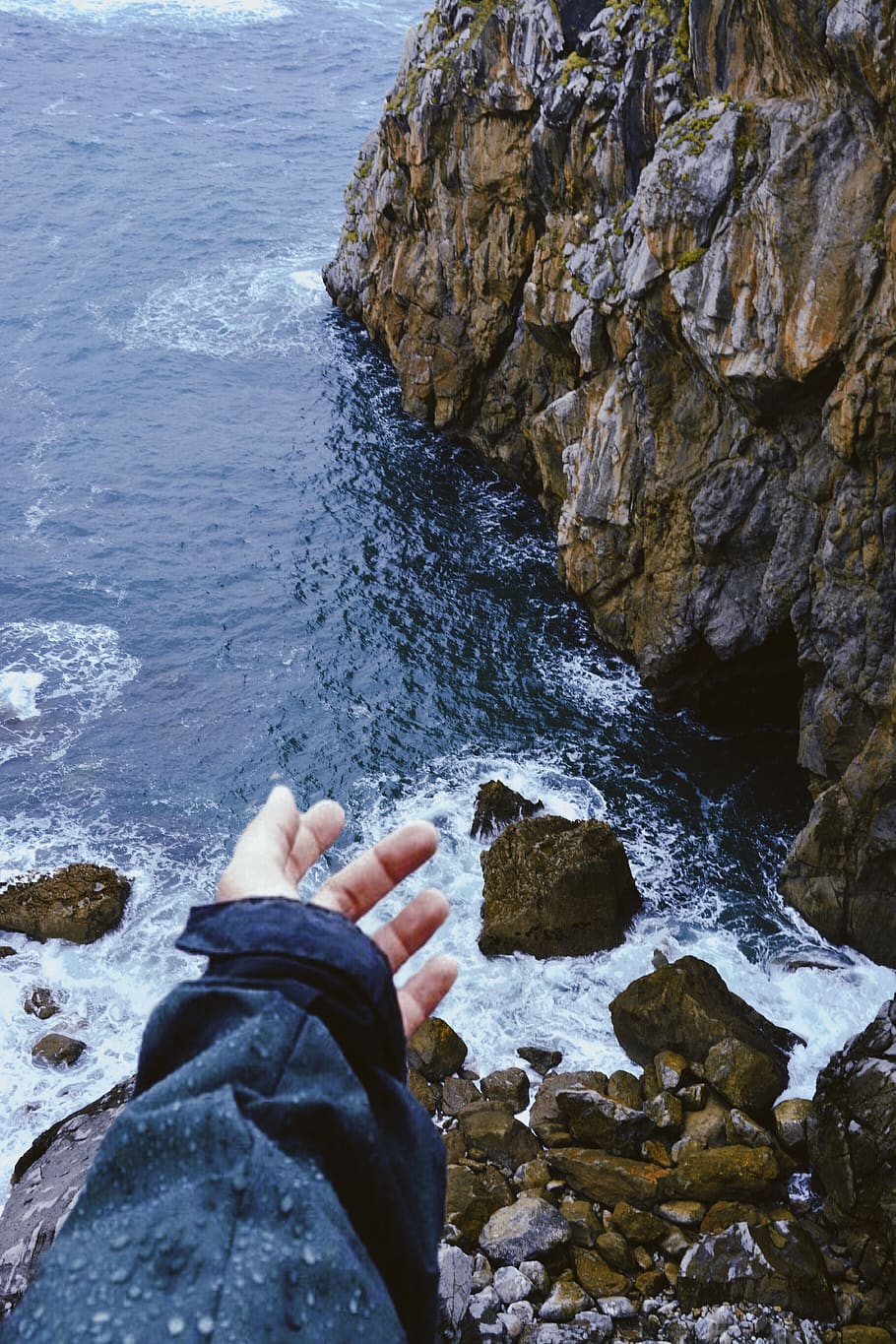 Person Standing On Rock Cliff Facing The Sea, hand, ocean, rocks HD wallpaper
