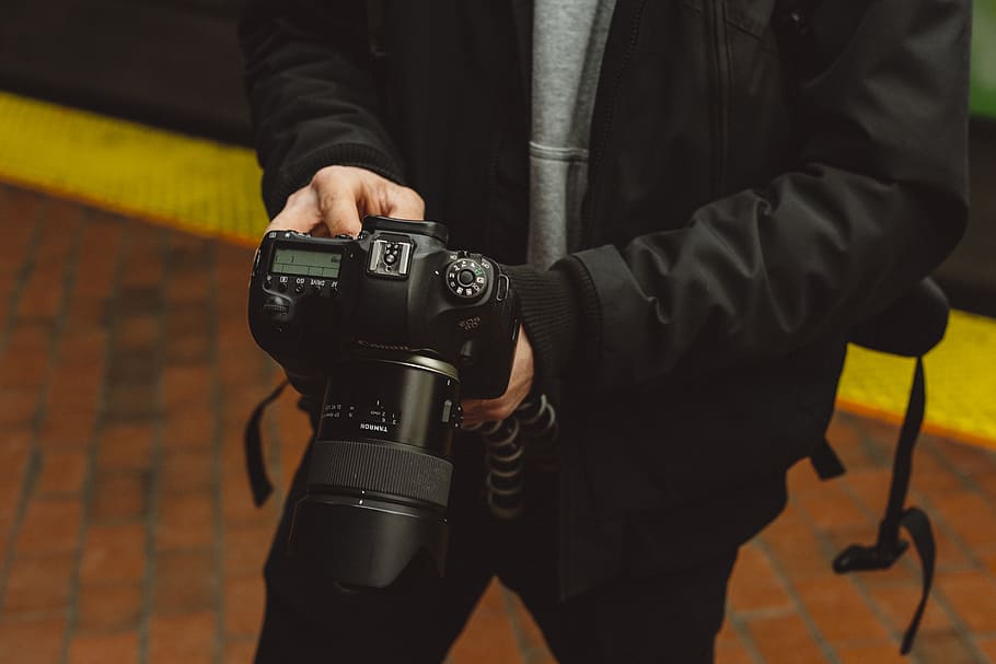 man in black jacket holding DSLR camera, electronics, person, HD wallpaper