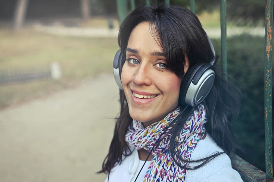 Young Woman Wearing Scarf While Using Headphones To Listen To The Music In The Park