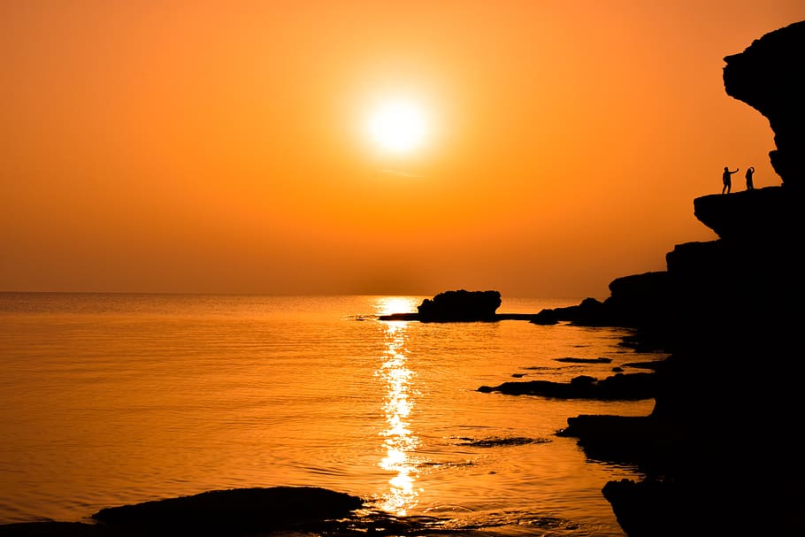 sunset, dusk, sea, water, rock, cliff, shadows, landscape, orange HD wallpaper