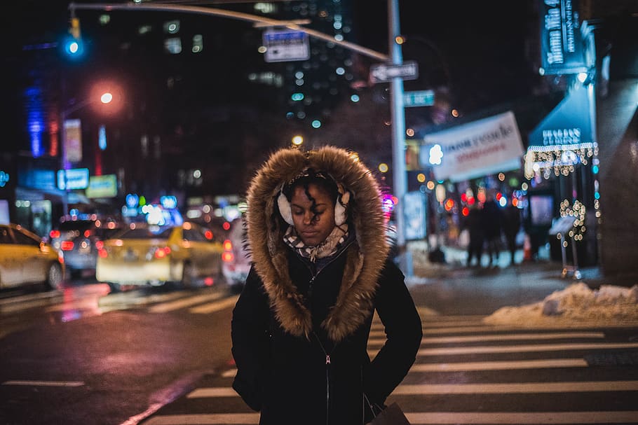 woman standing wearing parka coat at night-time, tarmac, asphalt