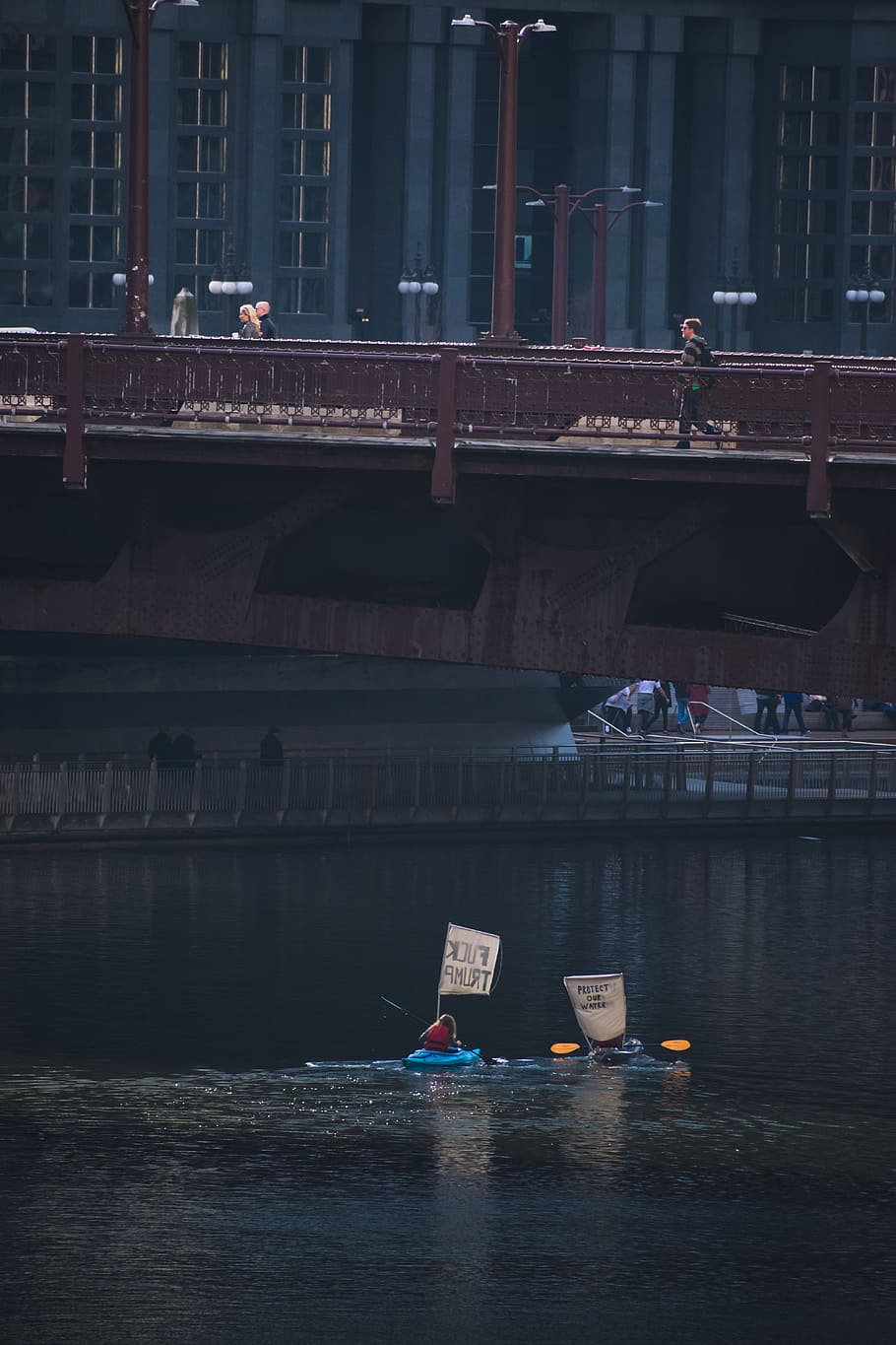 woman riding on blue kayak on body of water, protest, river, bridge