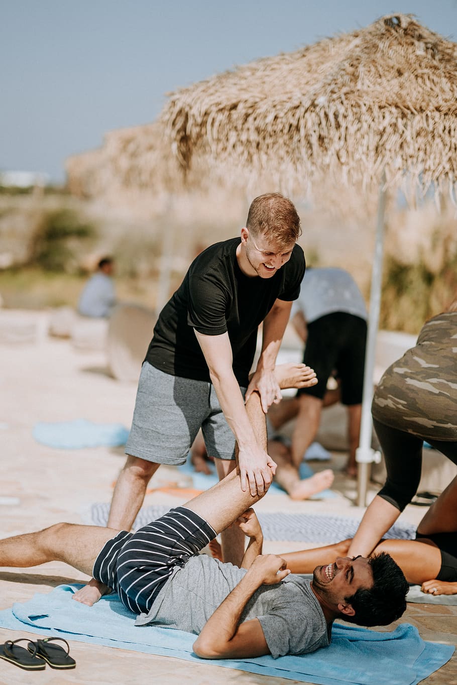 man pulling another man's leg while lying down in sand, lifestyles HD wallpaper
