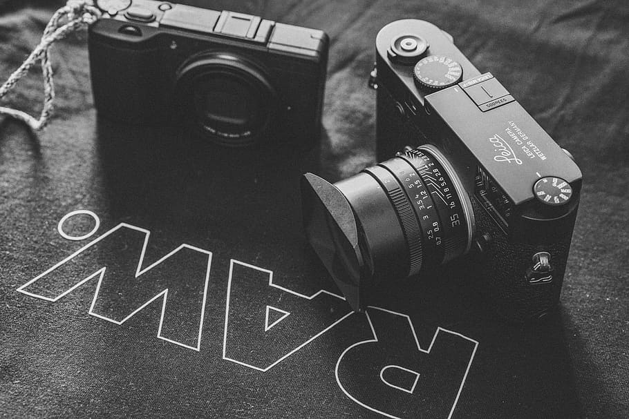 grayscale photography of two point-and-shoot cameras on black Raw. printed textile