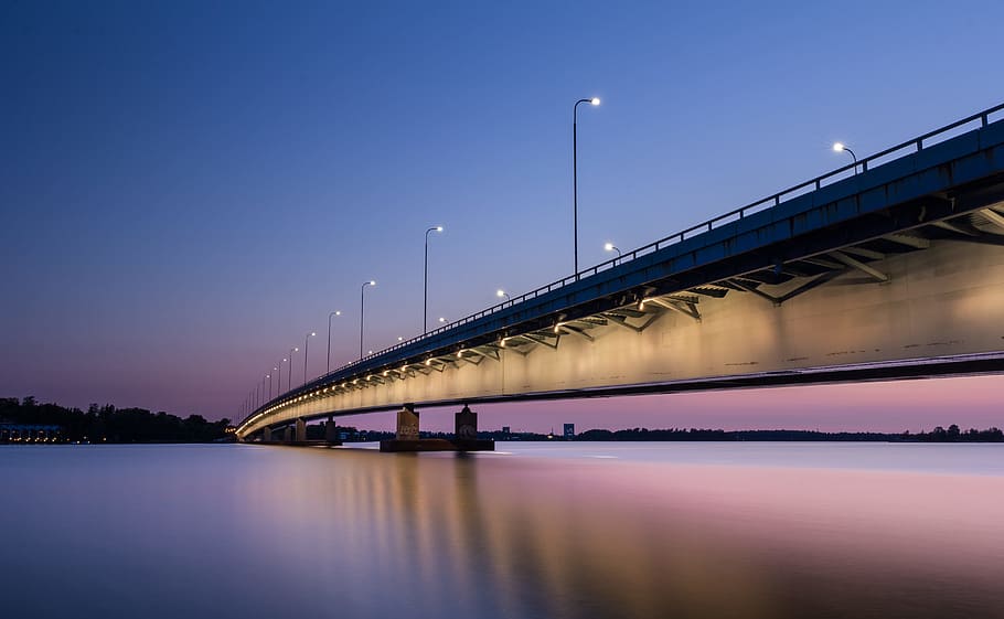 gray concrete bridge with body of water during nighttime, long exposure HD wallpaper