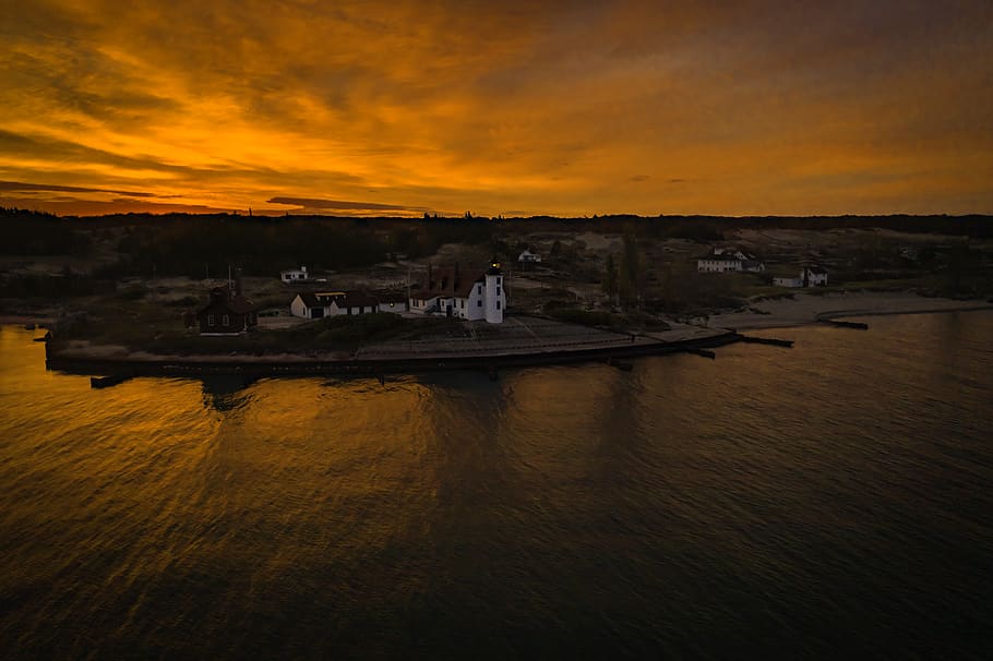 aerial photography of white building beside body of water under cloudy sky during golden hour