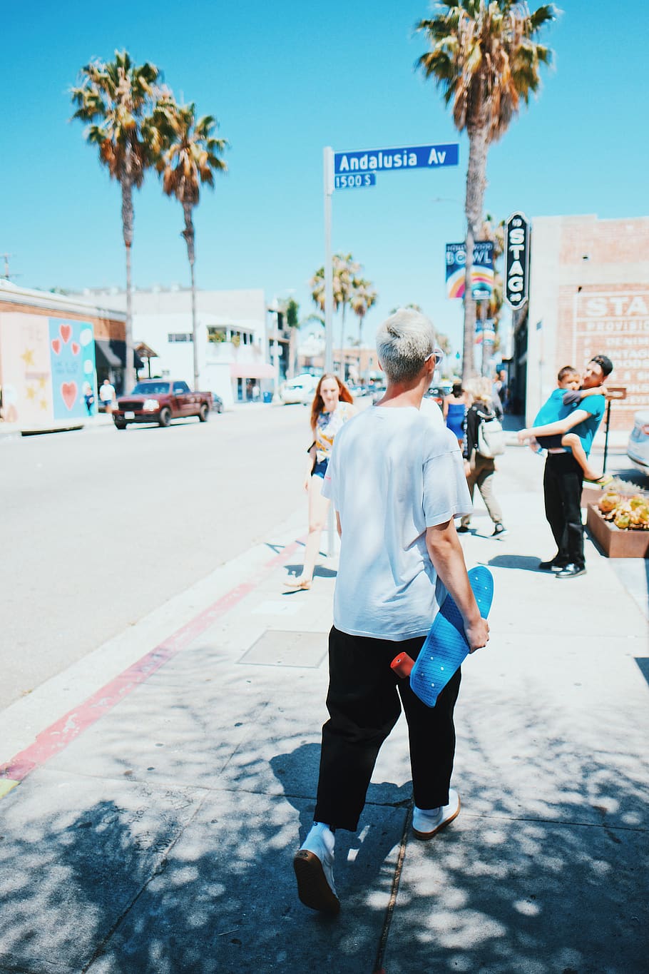 man walking while holding blue longboard, person, shorts, clothing HD wallpaper