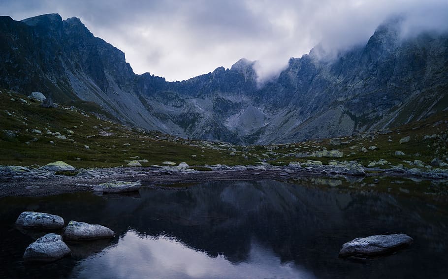 Water Besides Grey Stone Near Green Grass and Mountain during Cloudy Day HD wallpaper
