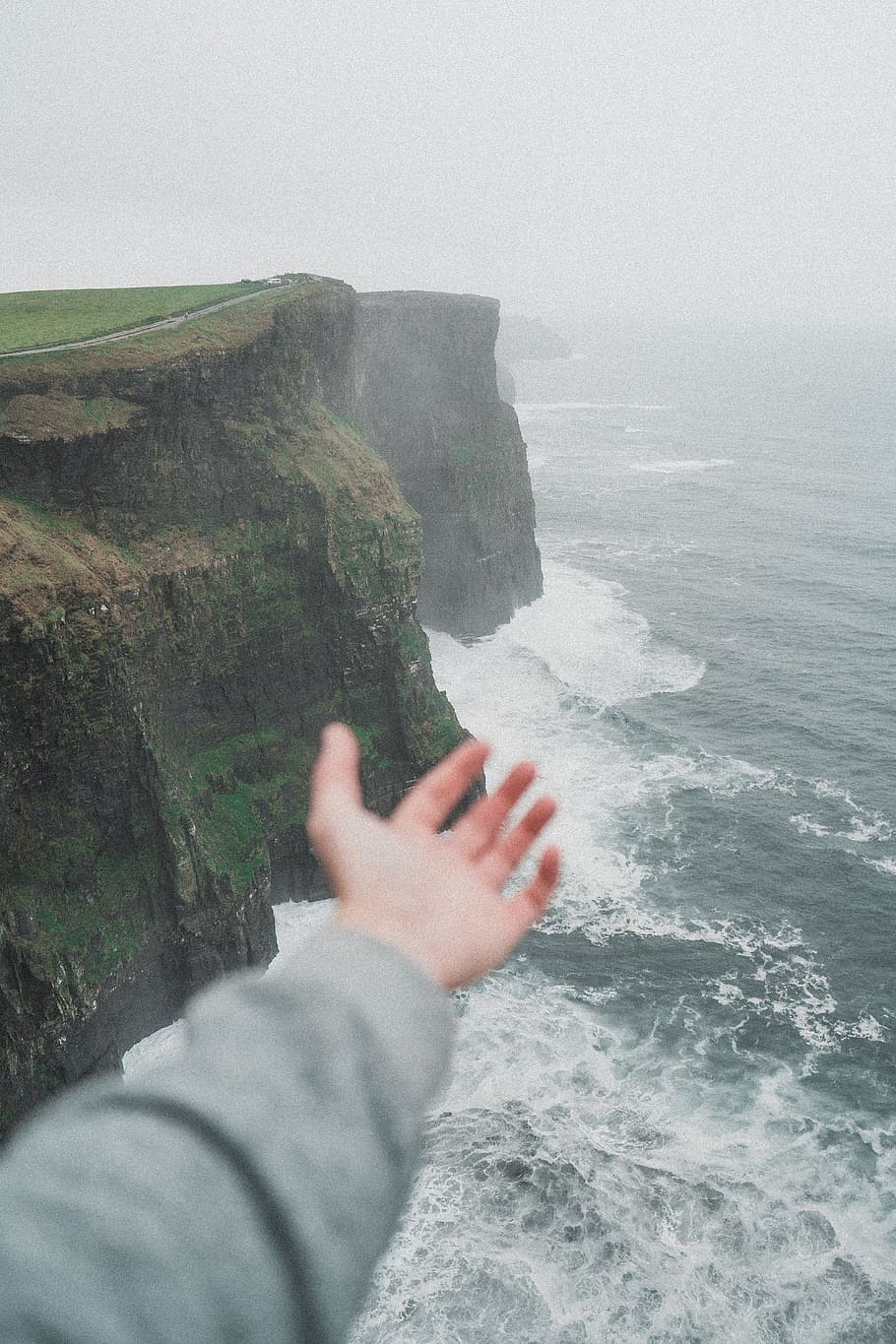 person standing on the cliff near the ocean, hand, cliffs of moher