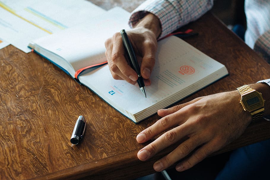 person sitting by the table writing something, pen, notebook HD wallpaper