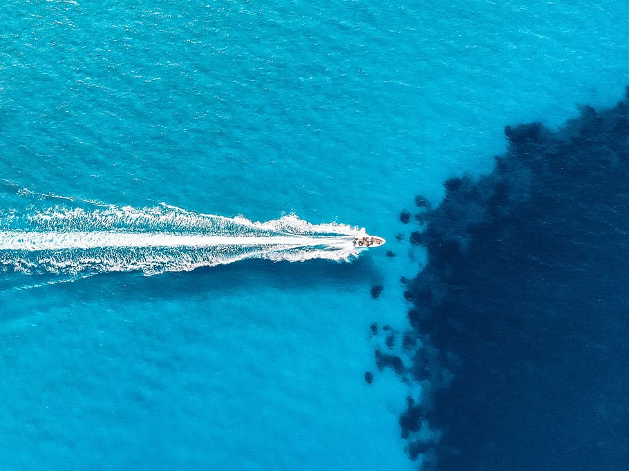 white motor boat on body of water during daytime, drone view