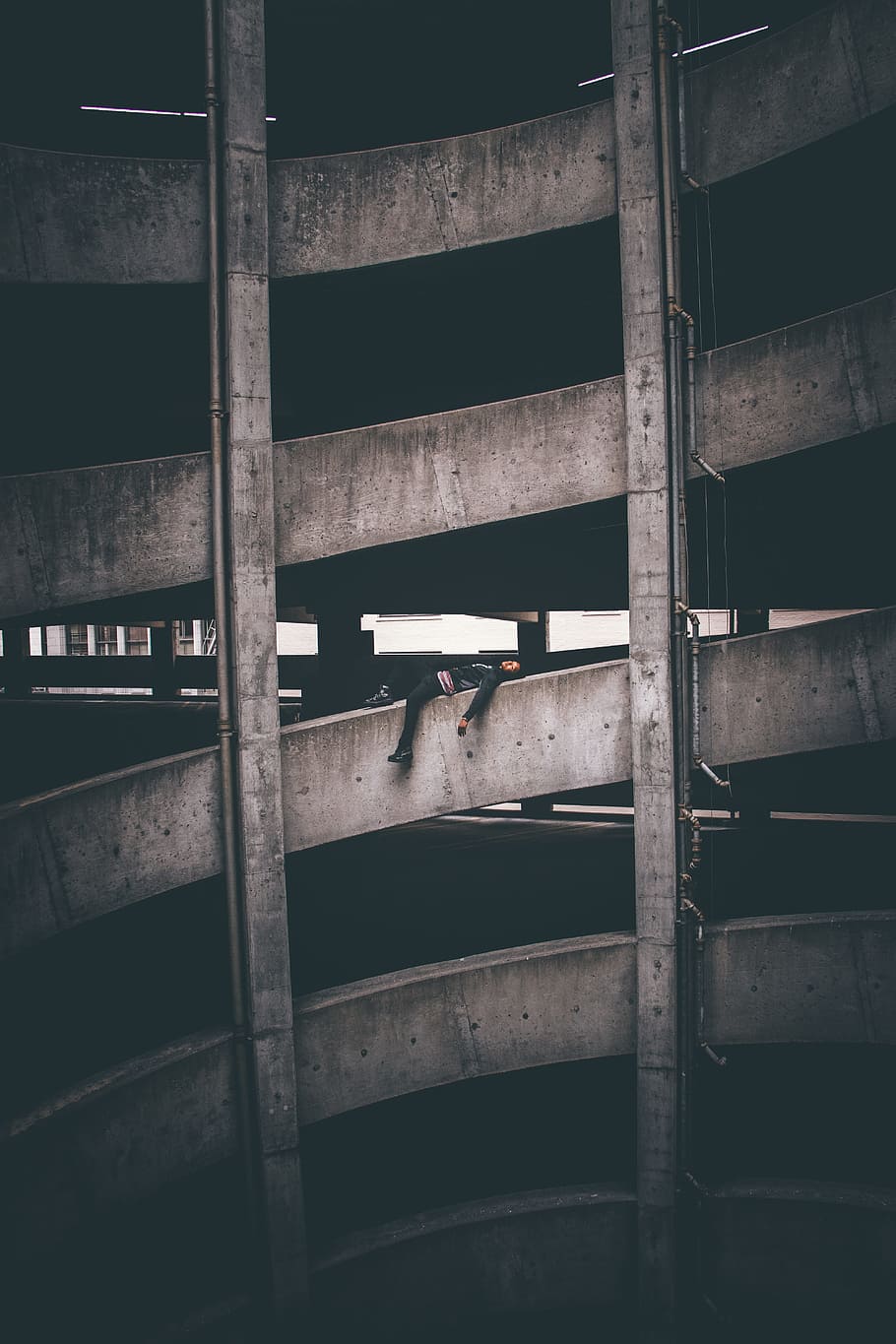 person lying on parking space during daytime, building, parking garage