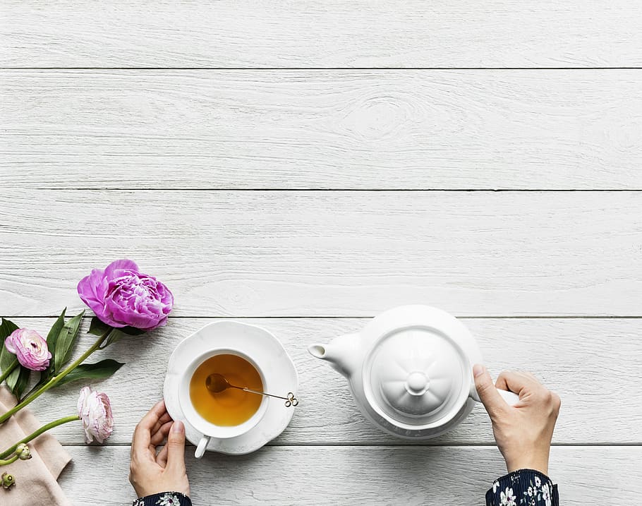 Person Holding White Ceramic Teapot on White Wooden Surface, background HD wallpaper