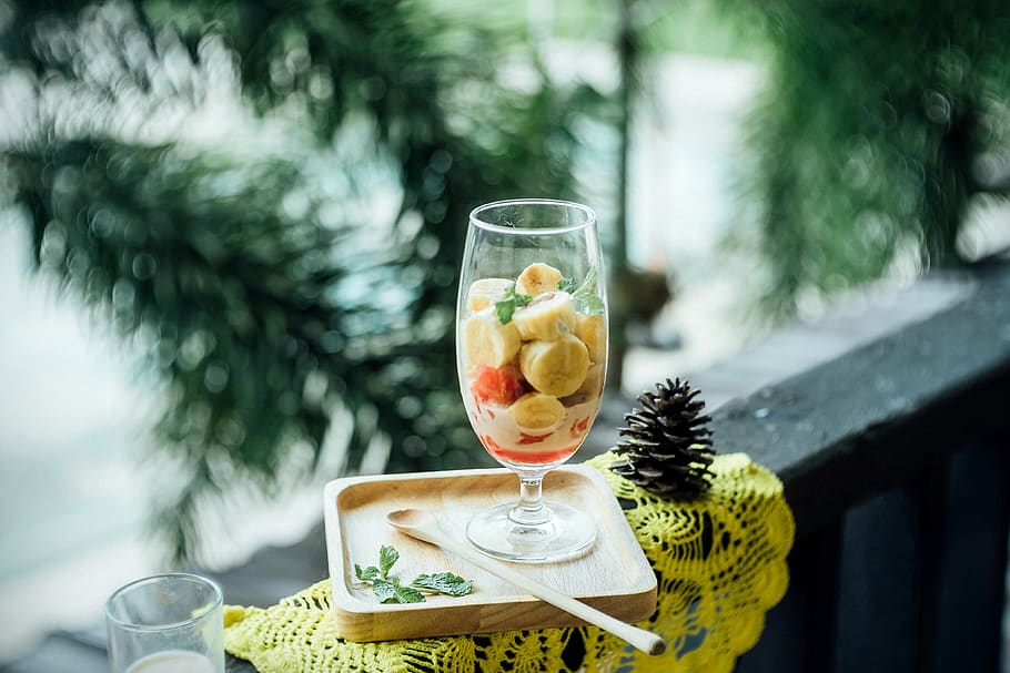 clear footed glass filled with fruits on brown wooden tray, tree