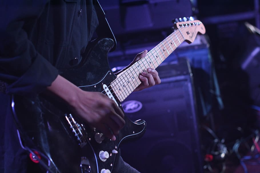 Person Using Black Fender Stratocaster, close-up, electric guitar