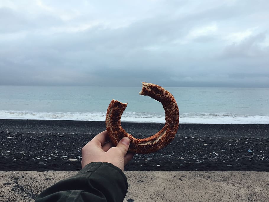 Person Holding Donut, beach, bite, daylight, doughnut, food, hand HD wallpaper