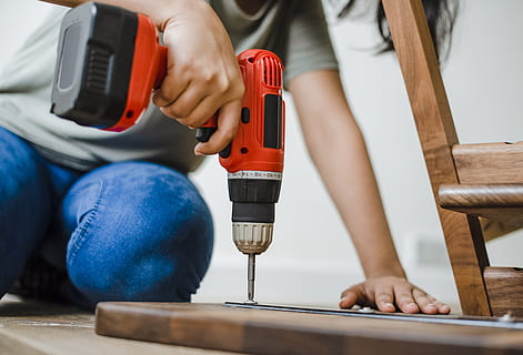 Person Using Red and Black Cordless Power Drill on Brown Wooden Bar HD wallpaper