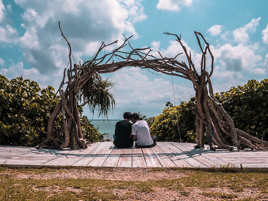 Man and Woman Sitting on Wooden Dock Under Cloudy Sky, branches HD wallpaper