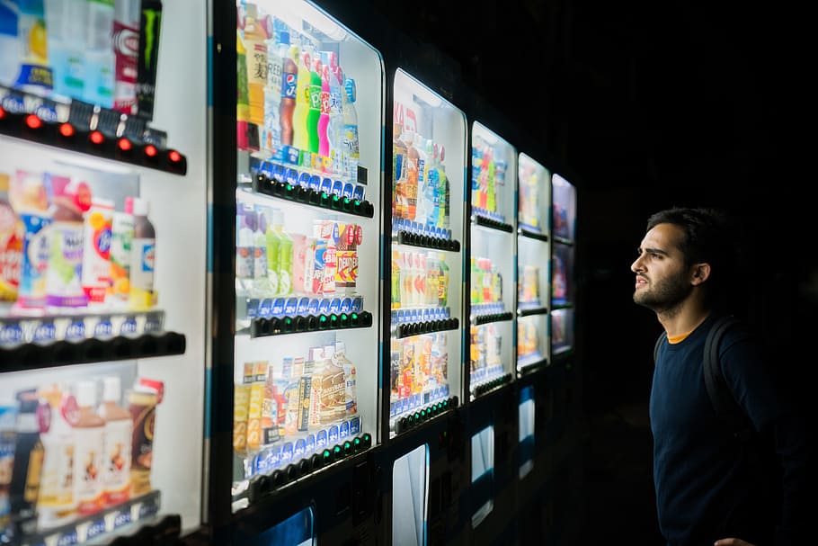 man on front of vending machines at nighttime, male, light, choice